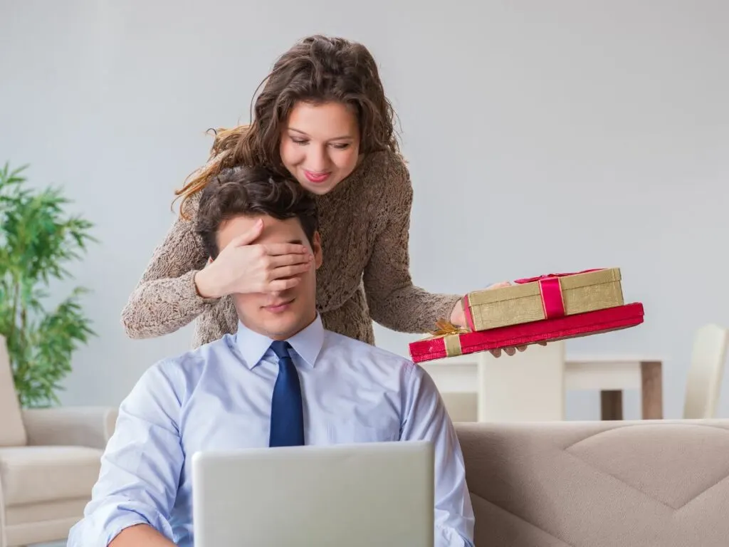 Wife surprising husband with beautifully wrapped gift boxes.