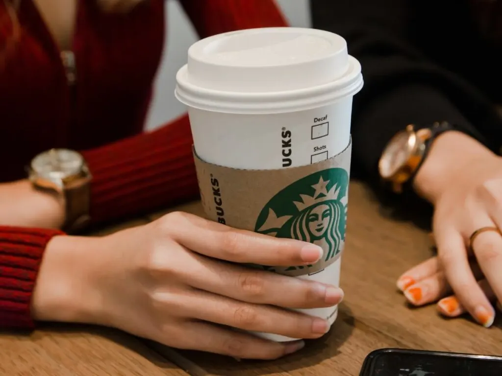 A woman's hand holding a venti cup of starbucks drink.
