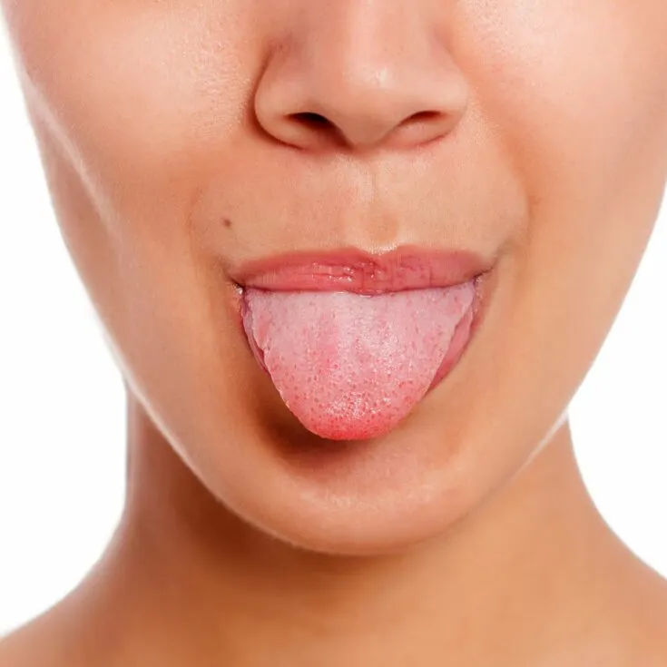 A woman demonstrating how to clean the tongue by sticking it out of her mouth.