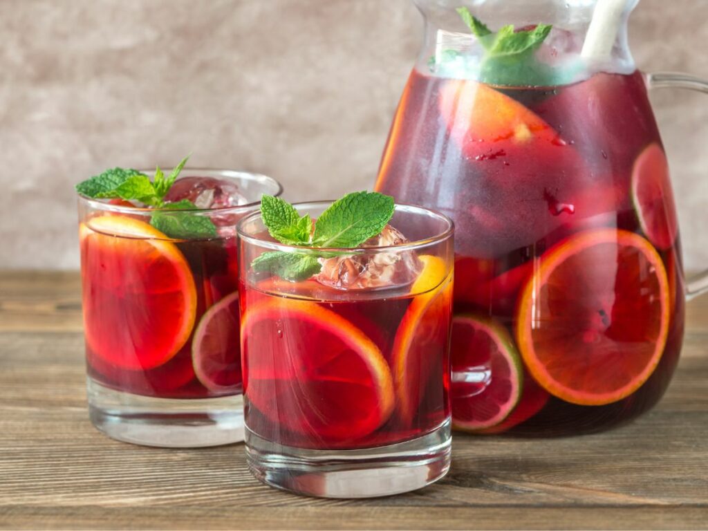 A pitcher of sangria with two glasses next to it.