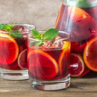 A pitcher of sangria with two glasses next to it.