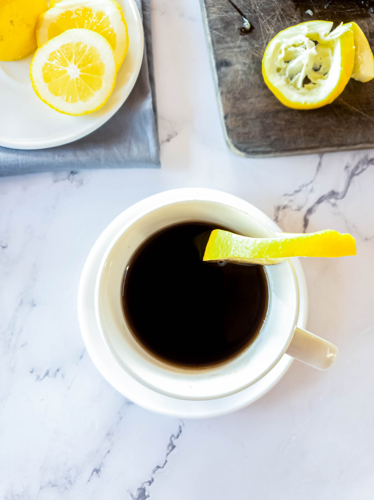 Cafe Romano served with lemon slice, more lemon in background.