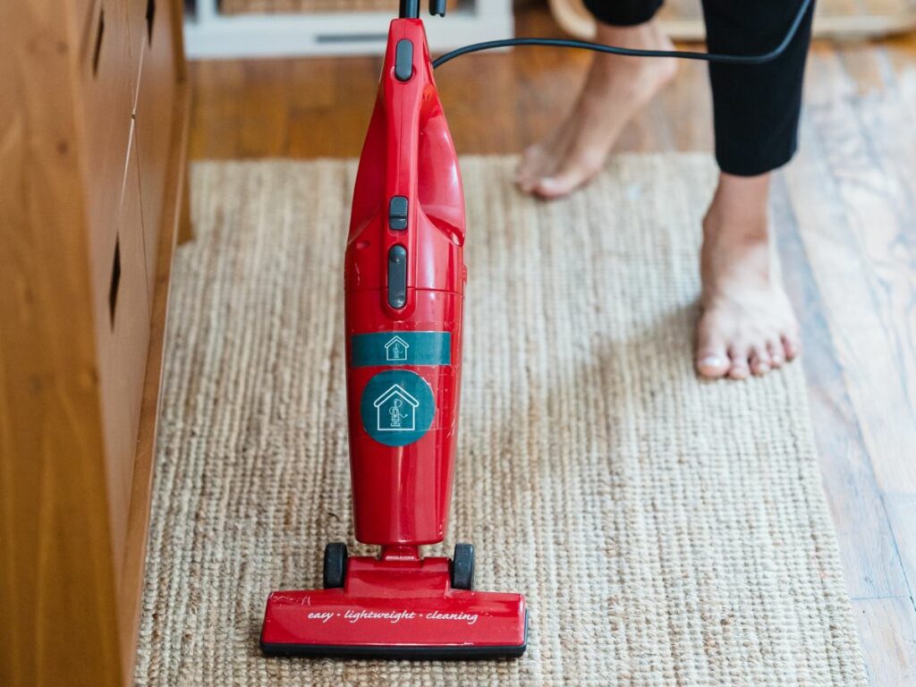 Woman vacuuming carpet with bare feet.