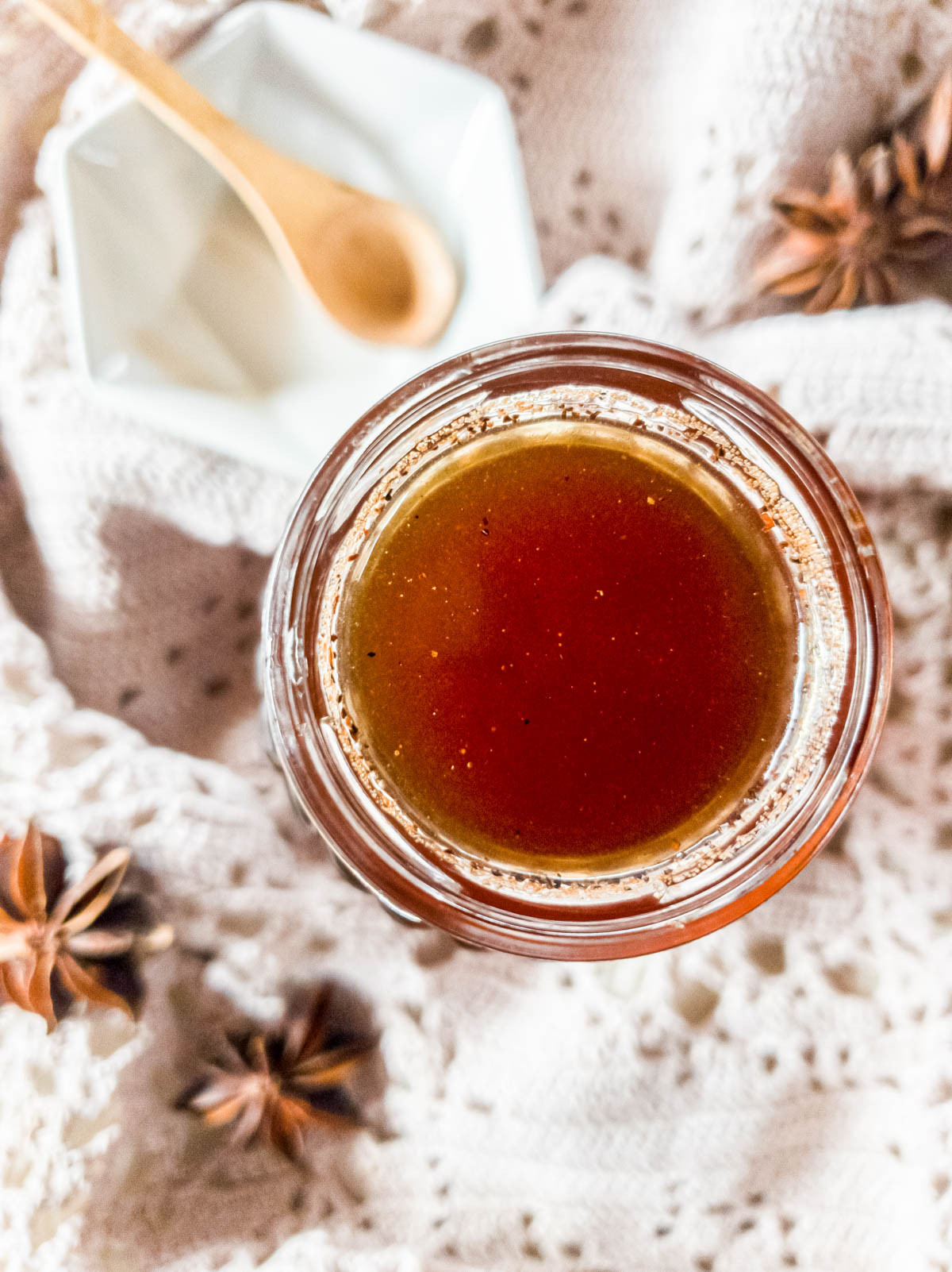 Chai syrup in jar with wooden spoon in white geometric bowl behind.