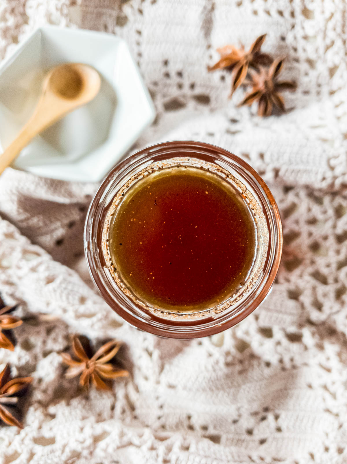 Simple syrup in glass jar on crochet table runner with whole star anise pods.