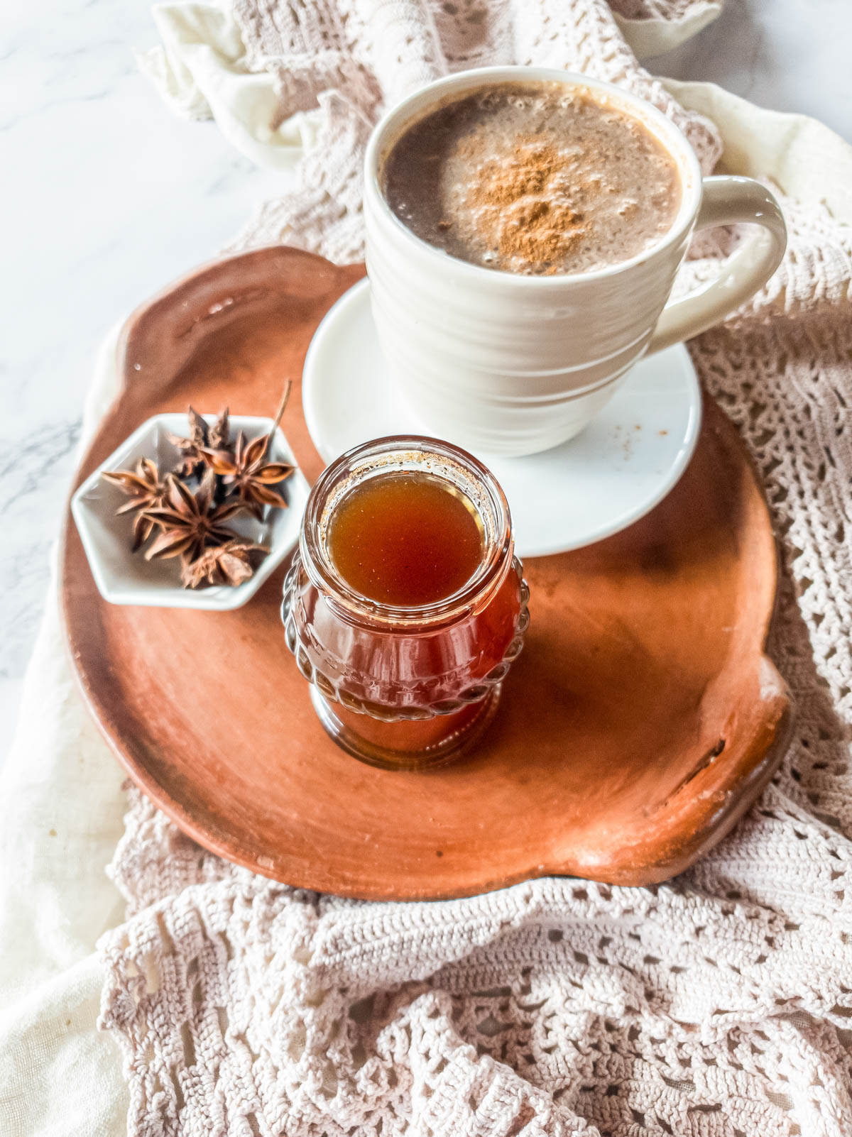 Terra cotta tray with chai latte and spiced simple syrup in glass jar.