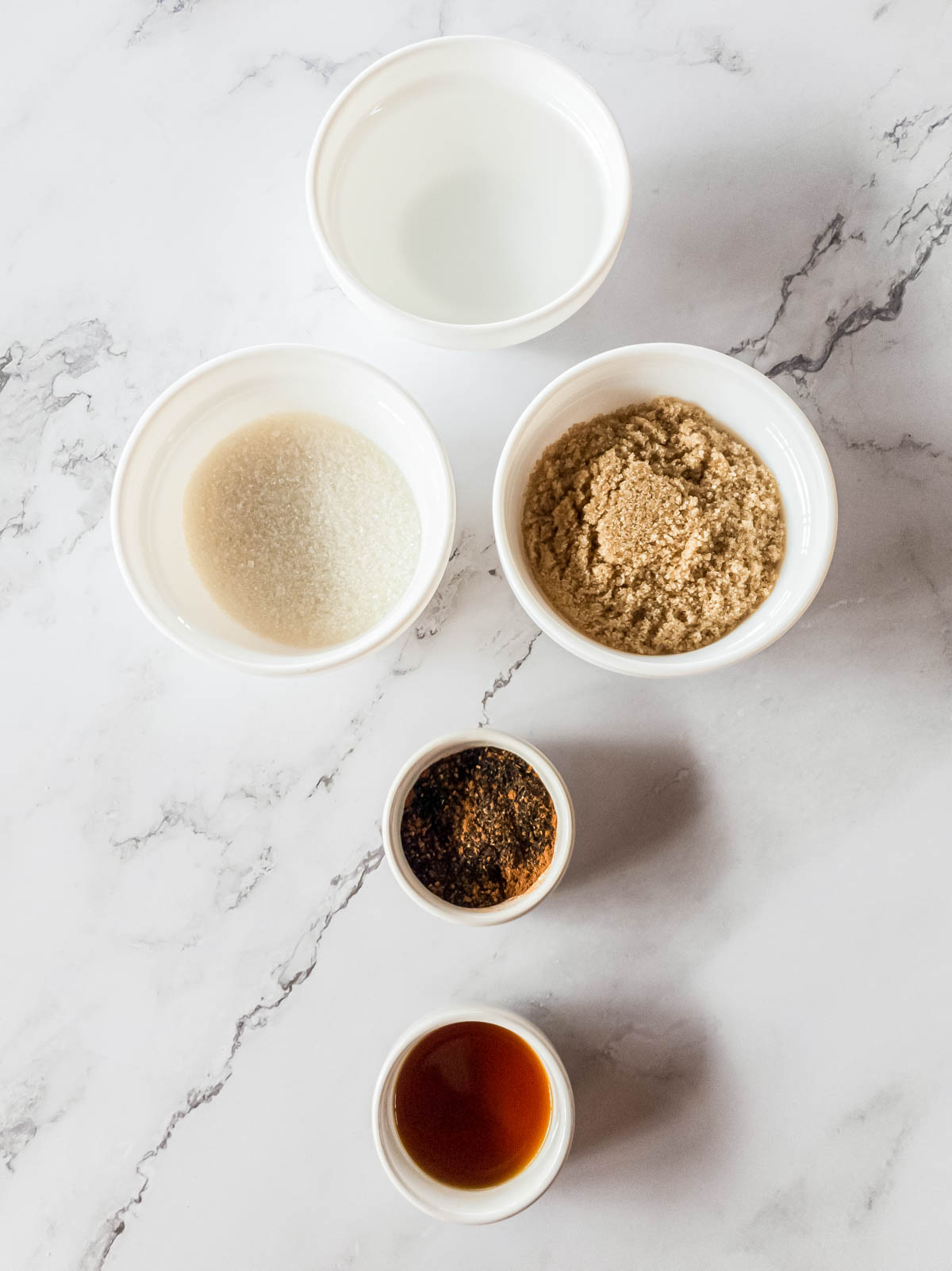 Raw ingredients for chai simple syrup in individual white bowls.