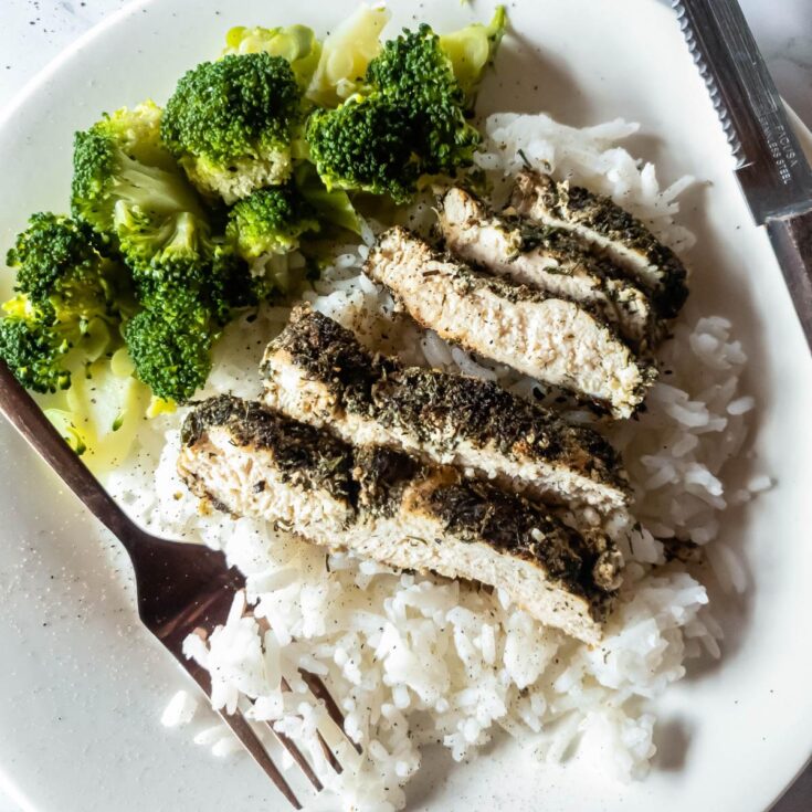 A picture of copper fork in rice with chicken slices and steamed broccoli.