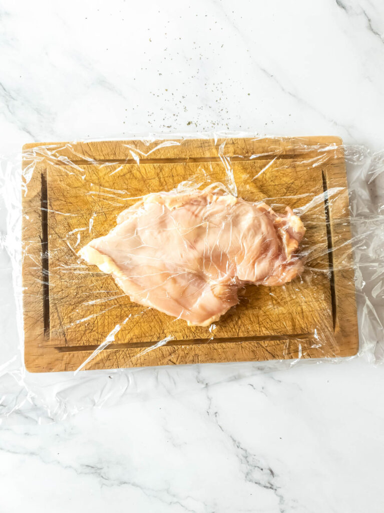 A picture of flattened chicken breast on cutting board.