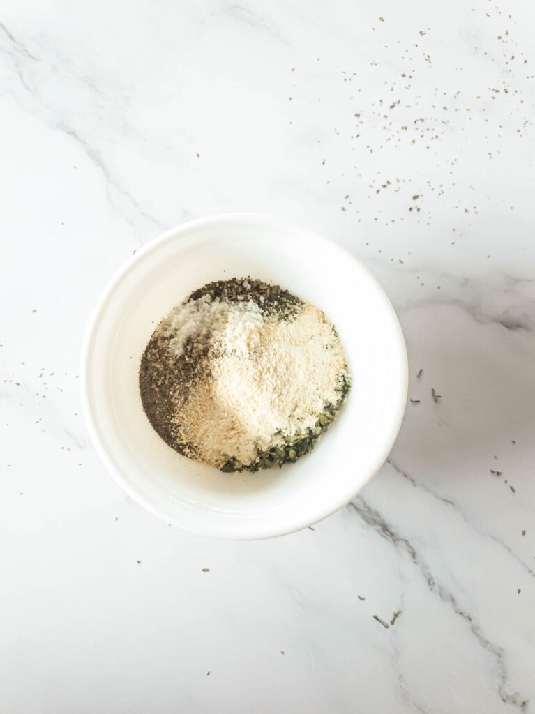 Herbs and salt in white bowl for coating chicken.