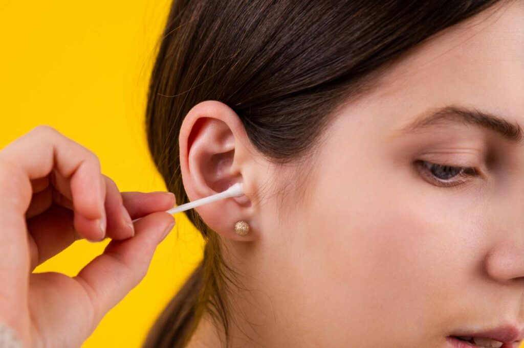 A woman using a cotton swab to clean her ears.