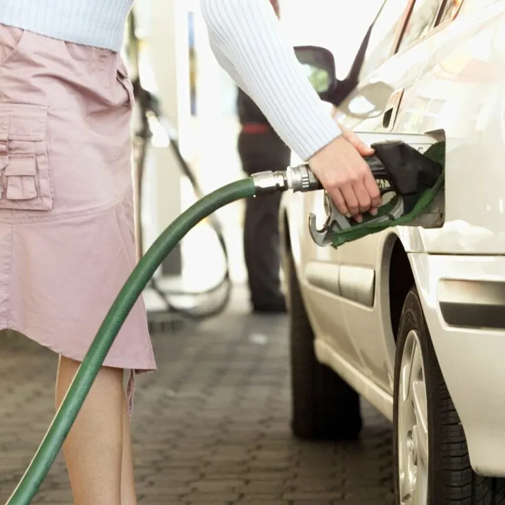 Woman pumping gas at station in pink skirt cropped square