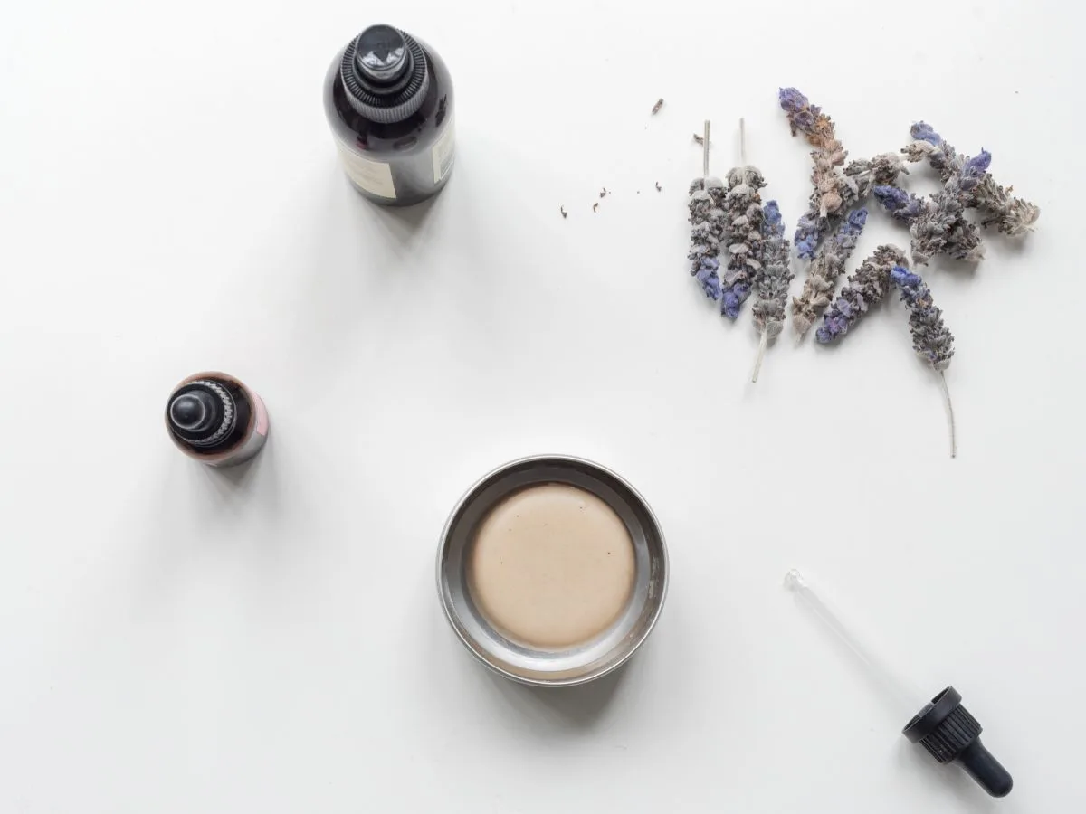 Simple array of essential oil bottles with lotion bar in tin, dropper bottle is on surface.