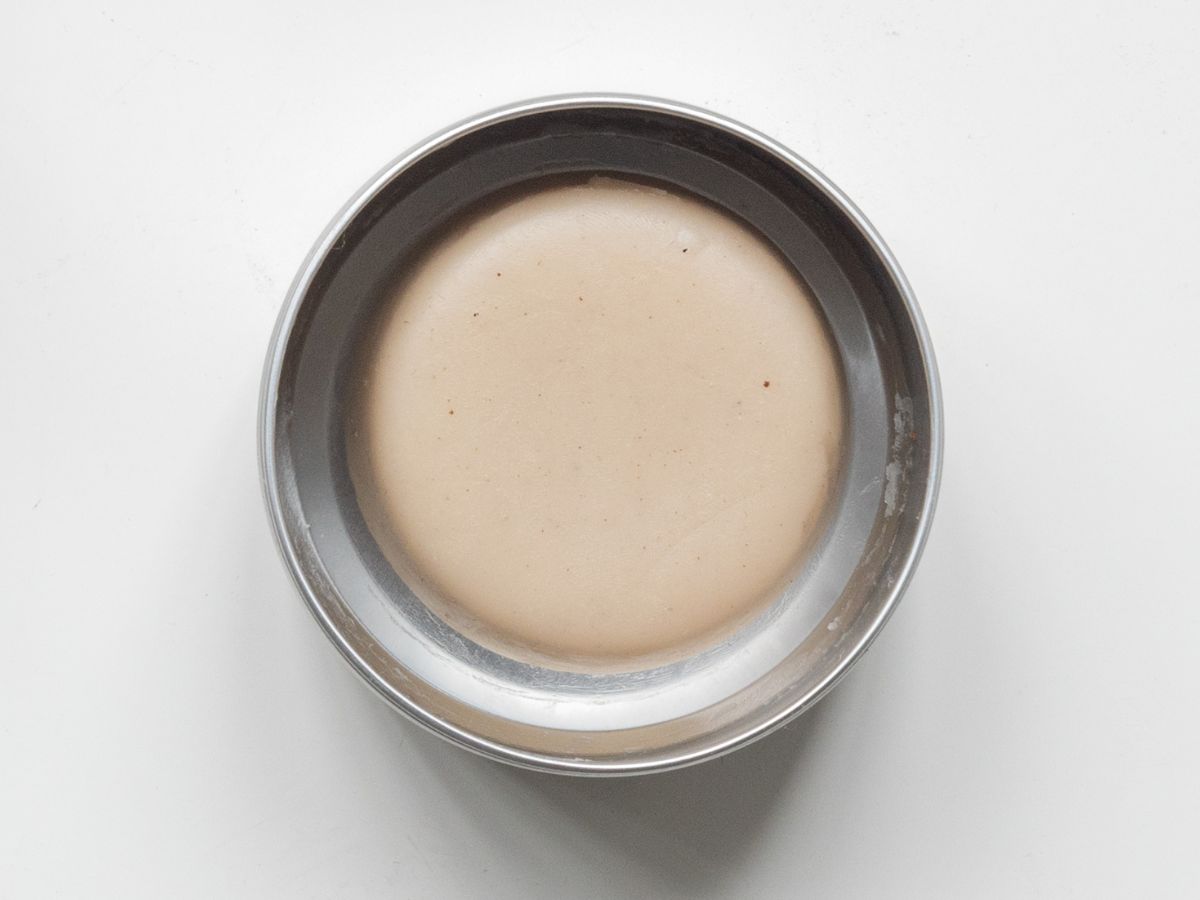 A lotion bar in container without lid.