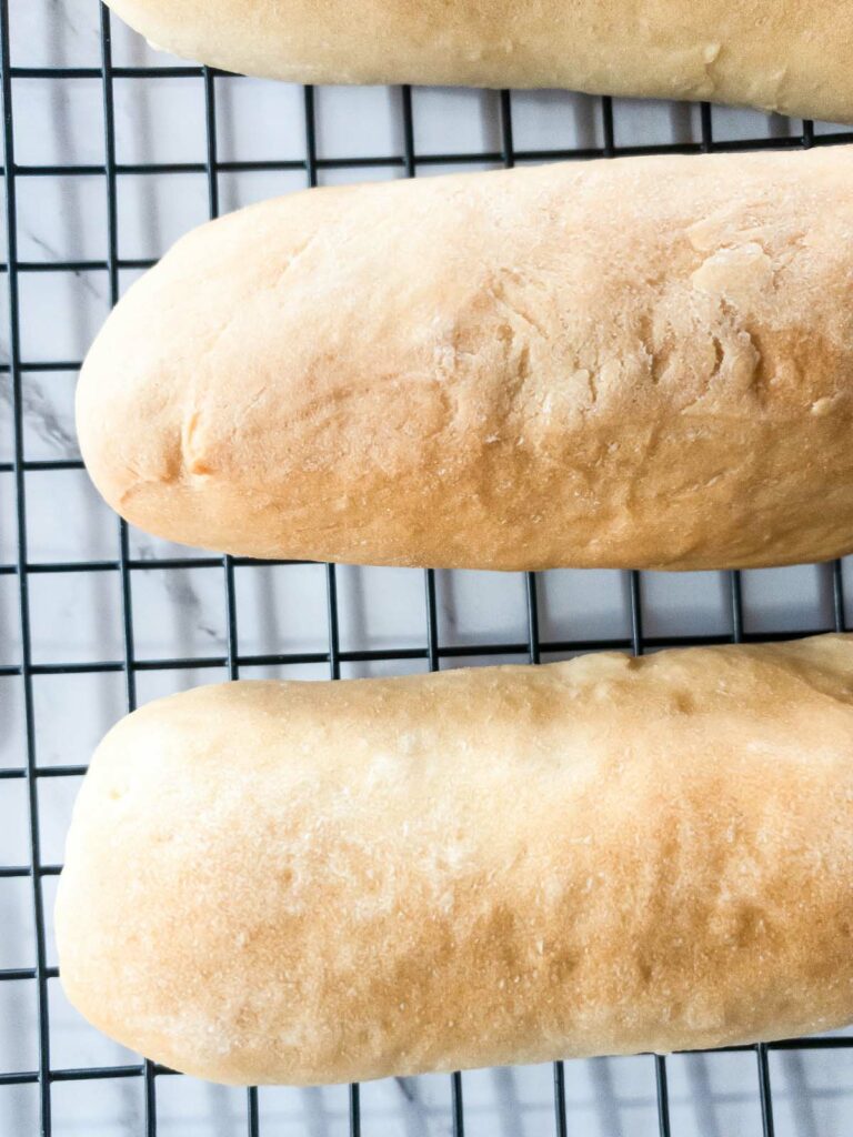 Three portions of Jimmy John's bread on a cooling rack.