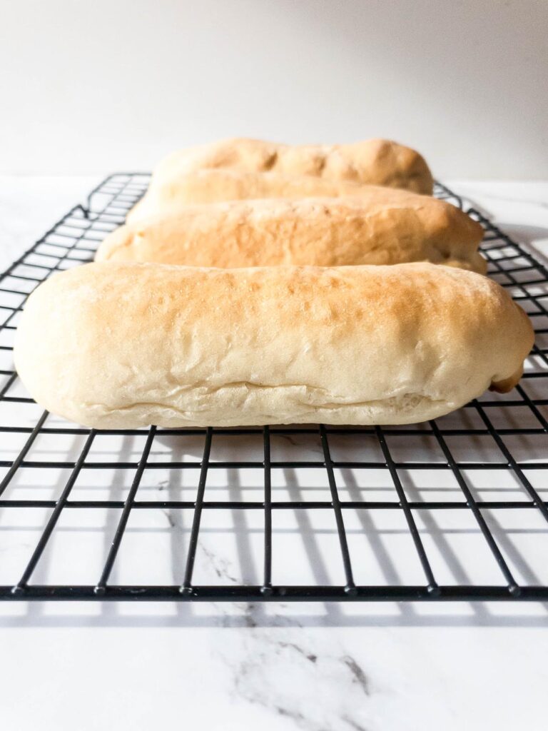 Three Jimmy John's loaves on a cooling rack.