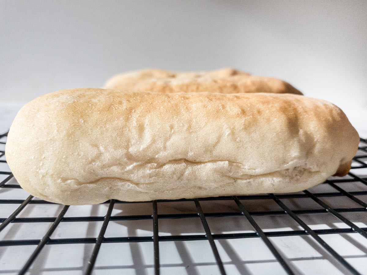 Two Jimmy John's loaves of bread sitting on a cooling rack.