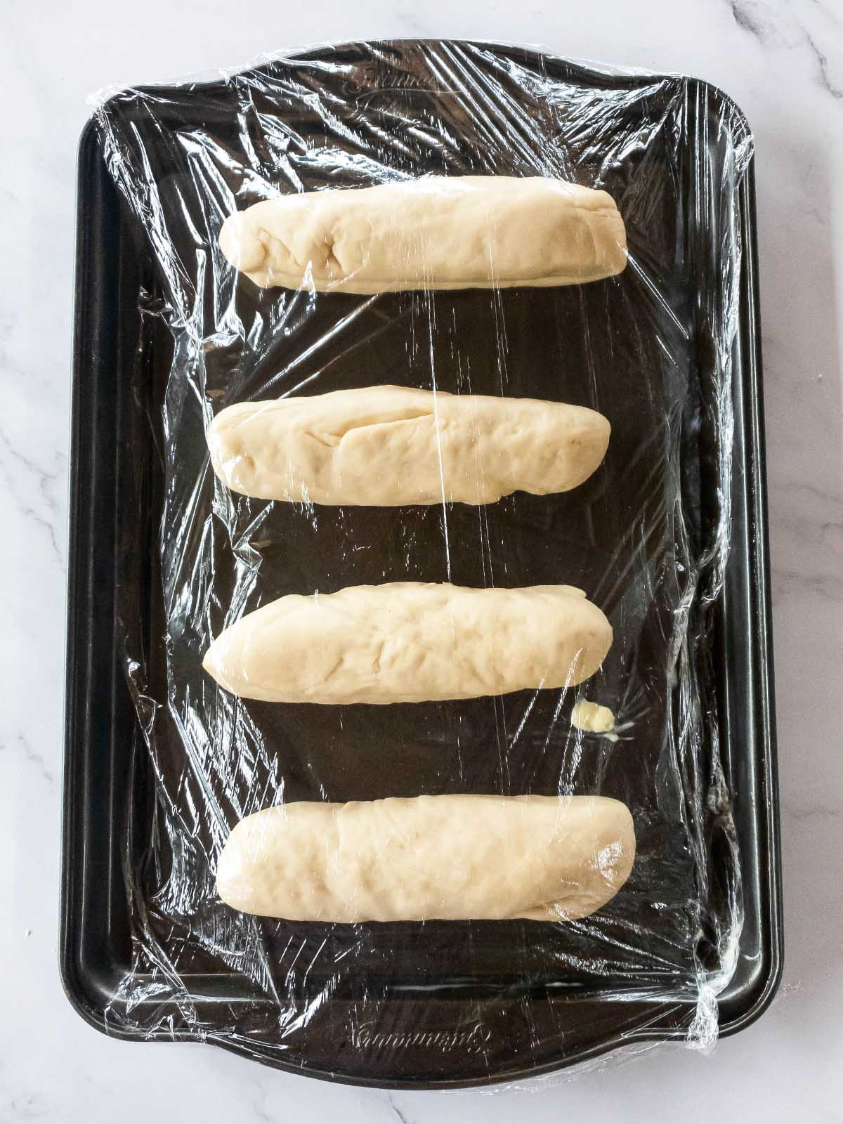Four pieces of jimmy johns bread on a baking sheet.