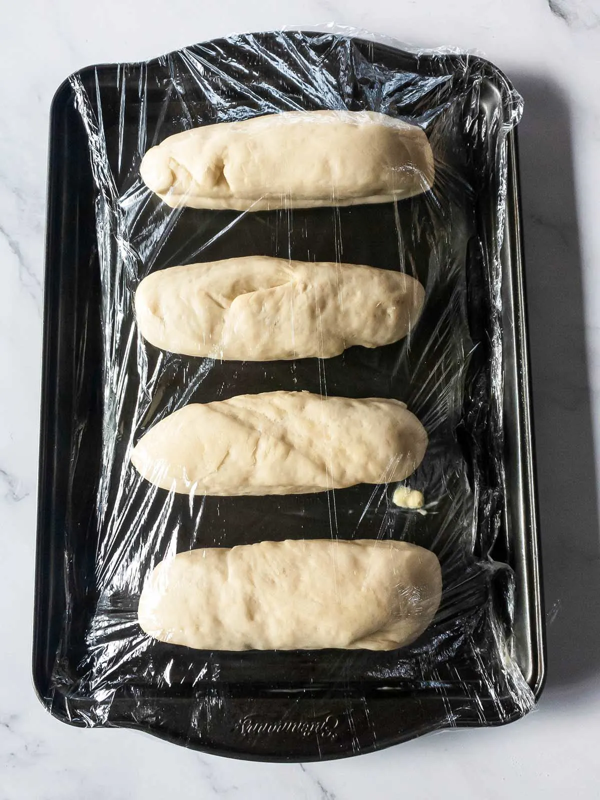 A baking sheet with four Jimmy John's bread on it.