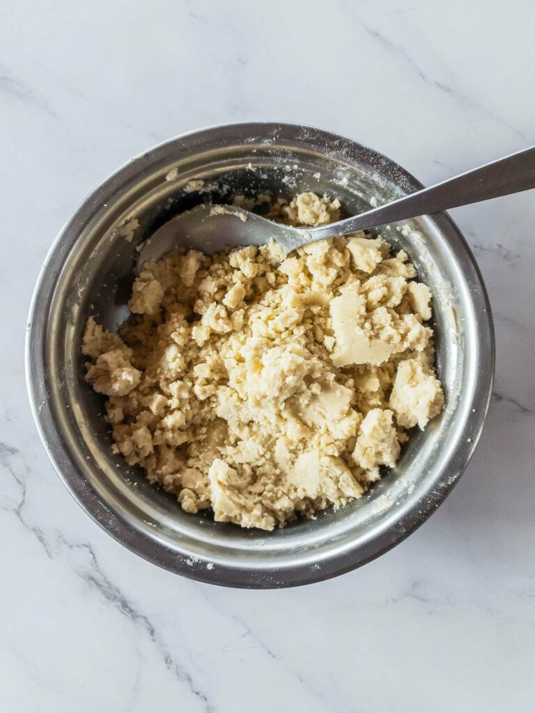 A spoon in a bowl, mixing flour and oil together.