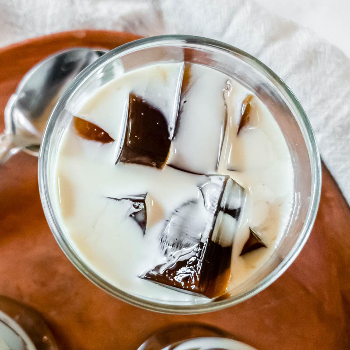 A picture of coffee jello in a glass with milk.