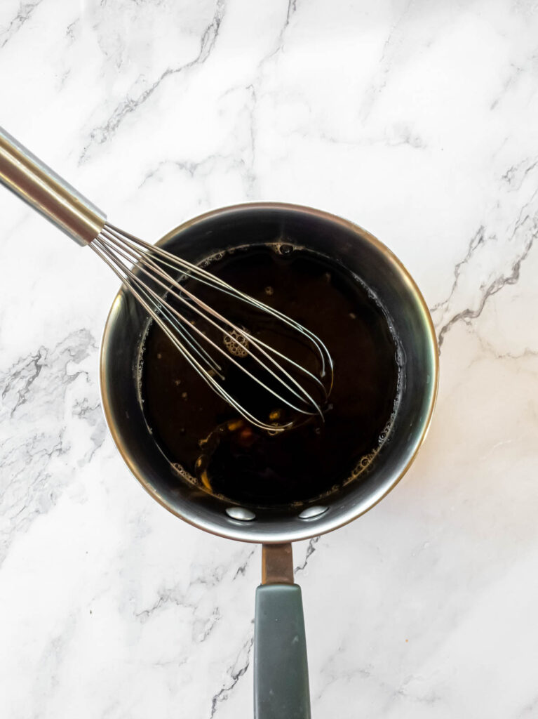 Stainless steel whisk in small sauce pan of coffee.