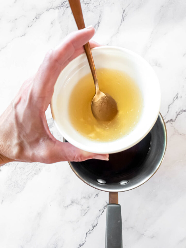 A person is adding gelatin to coffee into a pot.