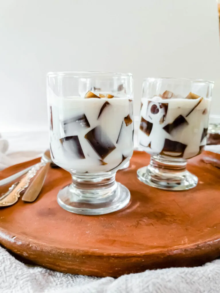 Two glasses of saiki k coffee jelly ice cream on a wooden tray.