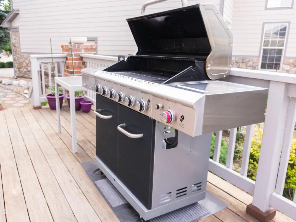 A barbecue grill on the deck of a house.