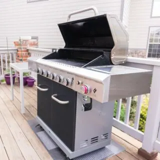 A bbq grill on a backyard deck outside.