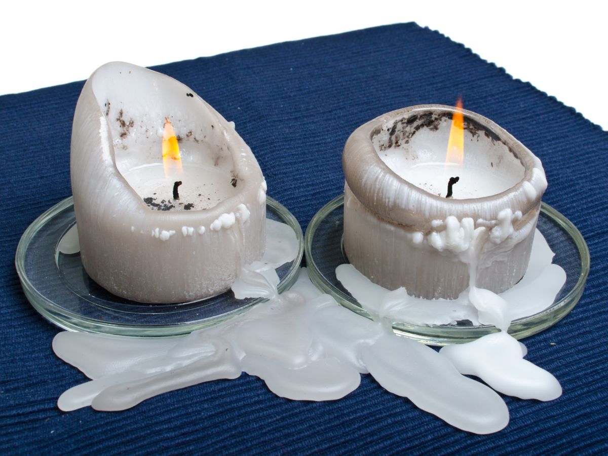 A picture of two white candles melting on navy blue carpet.