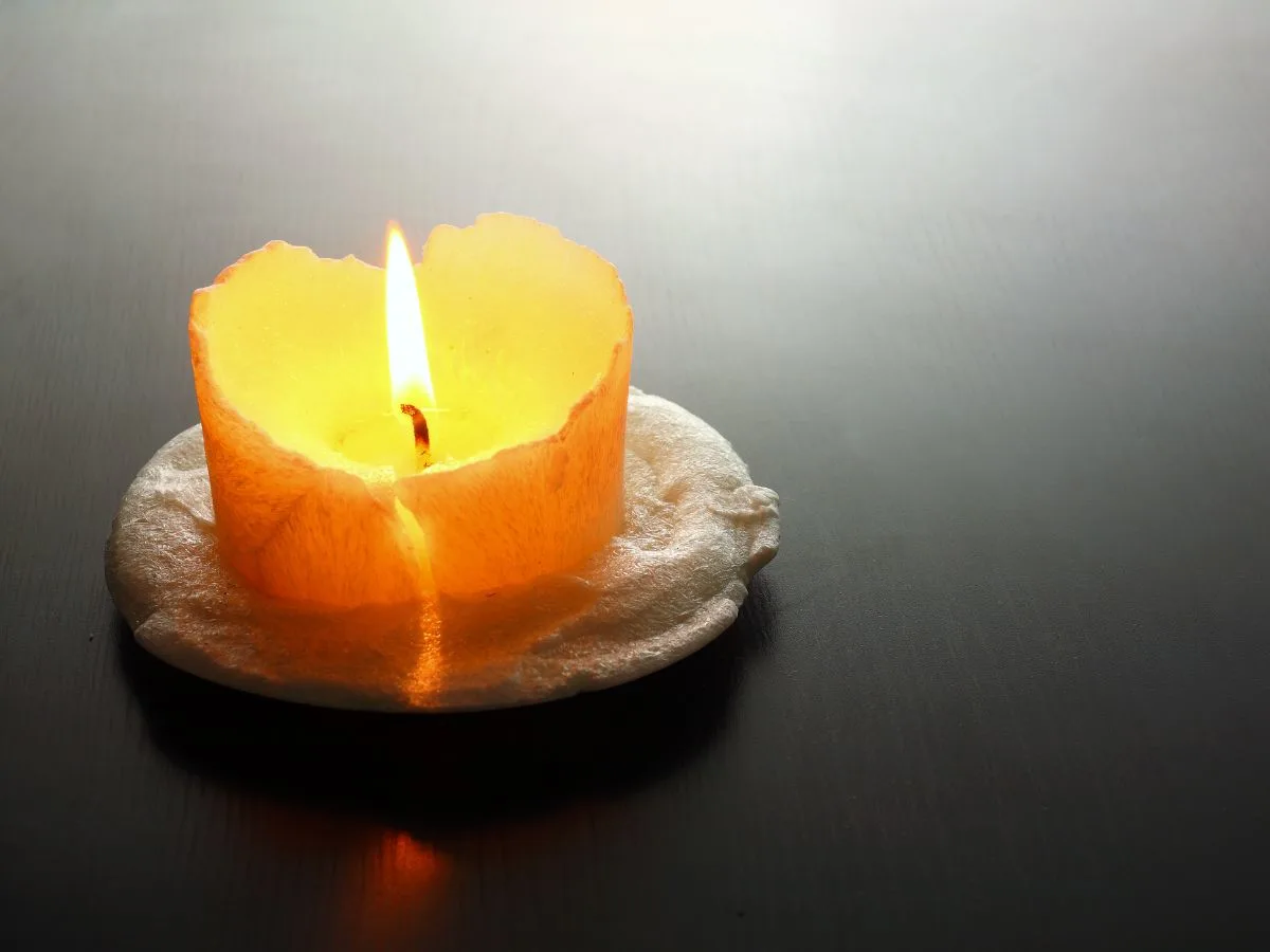A picture of one orange candle burning low.