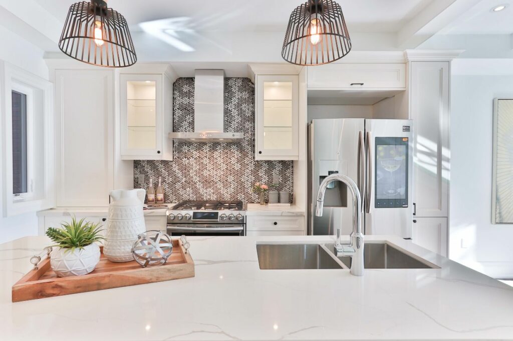 A white kitchen with stainless steel appliances and white counter tops.