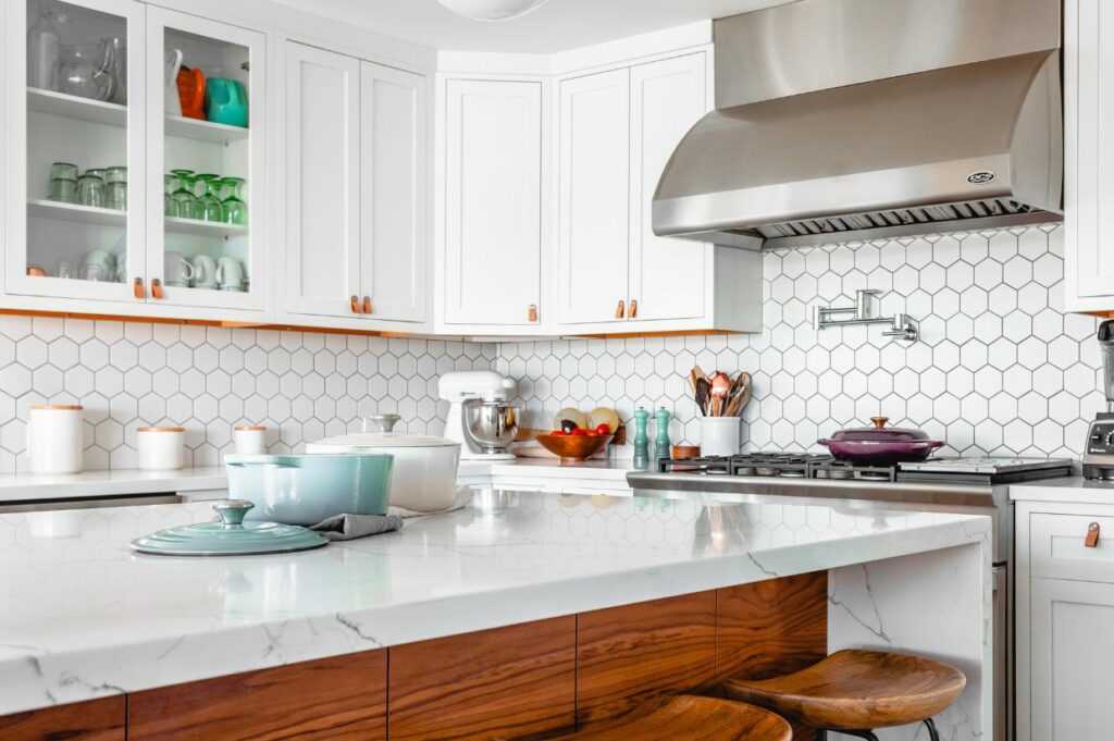 A kitchen with white cabinets and wooden stools.