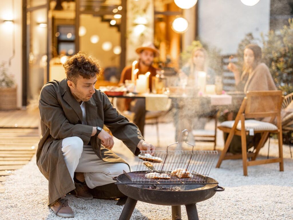 A group of people cooking food at a backyard bbq.