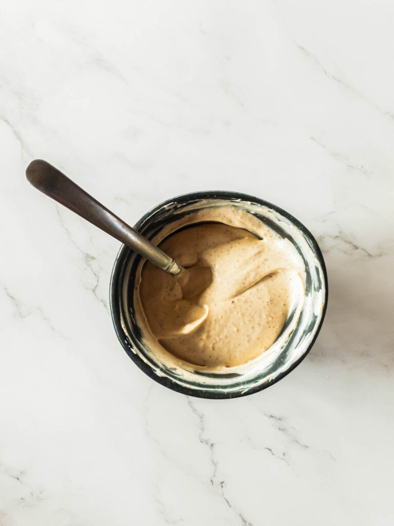 Spicy mayonnaise in ceramic bowl with a stirrer.