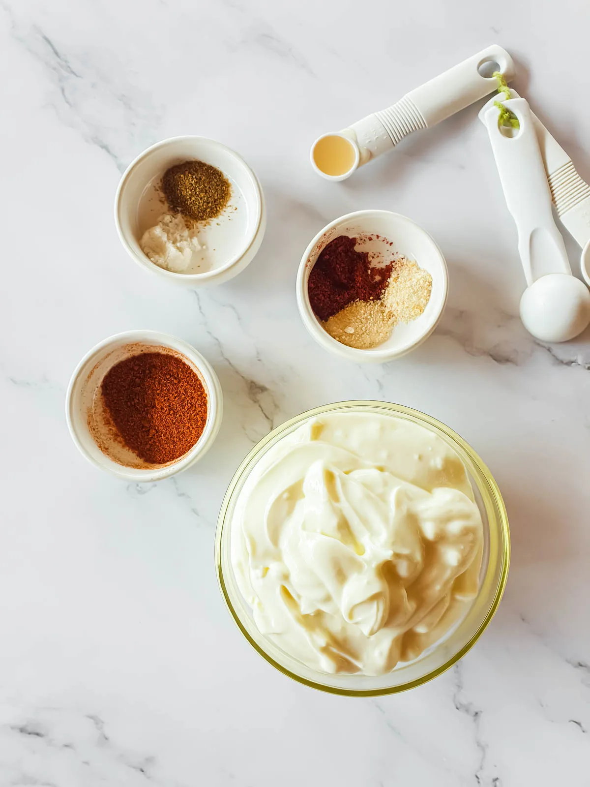 Ingredients for Popeyes spicy mayonnaise in separate bowls next to a set of measuring spoons.