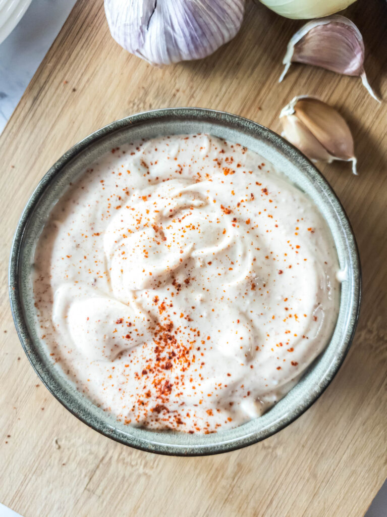 Spicy mayo with paprika garnish in ceramic bowl.