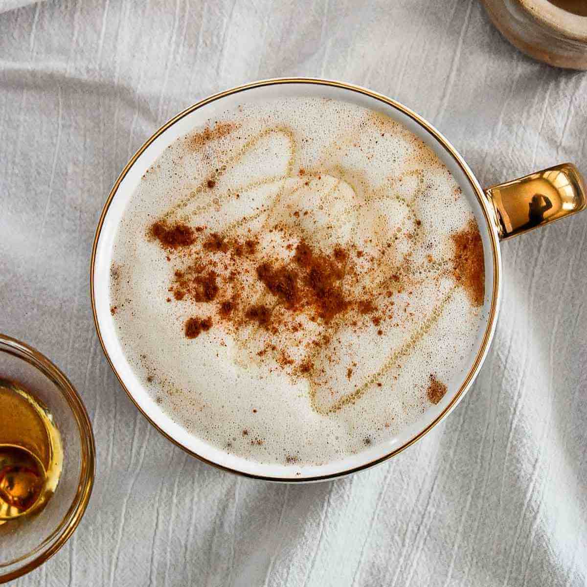A cup of latte with cinnamon and honey.