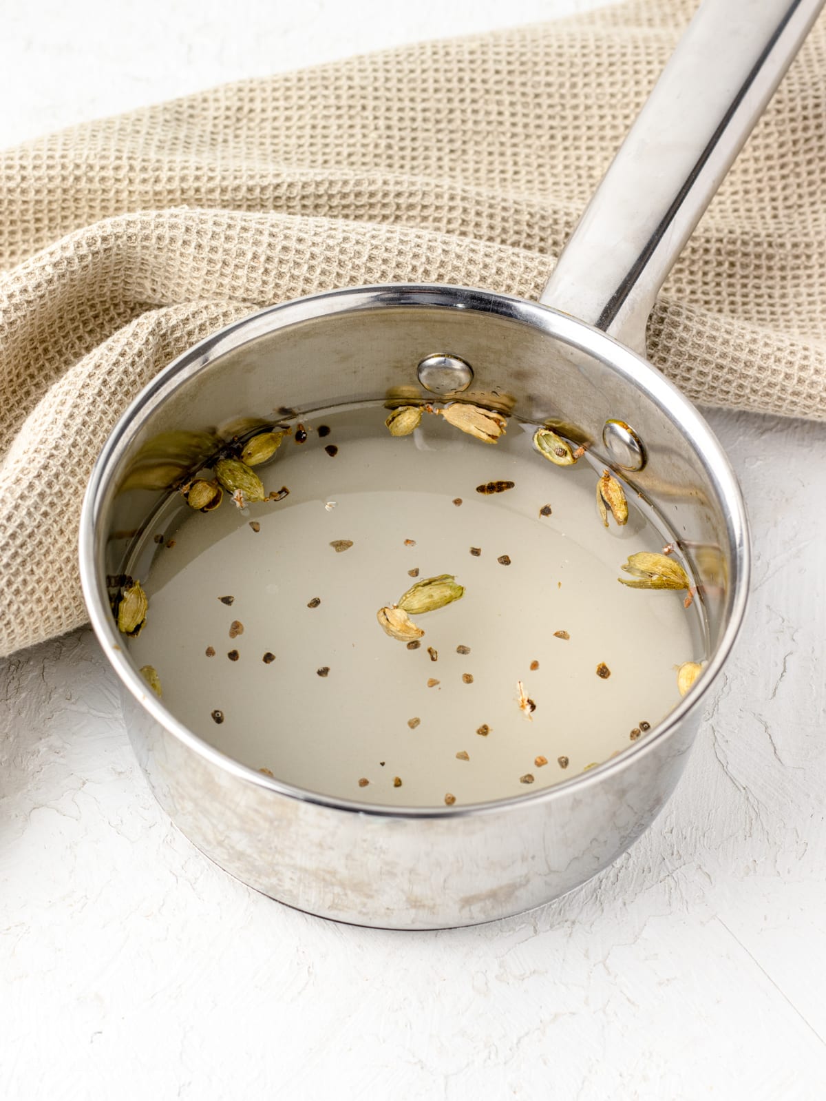 Cardamon pods in a pan on a white background.