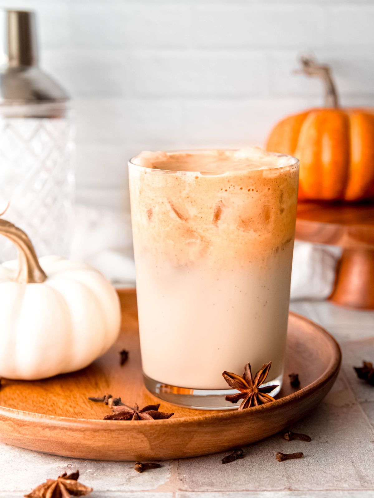 A pumpkin spice latte on a wooden plate.