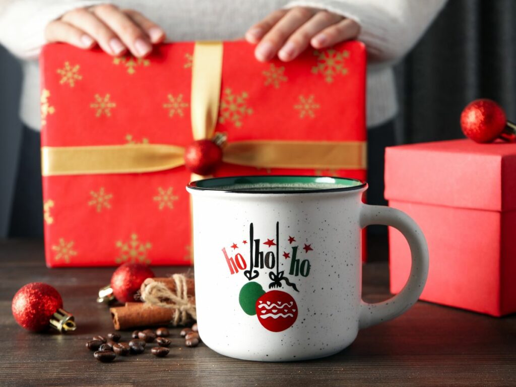 A woman is holding a mug with a christmas ornament on it.