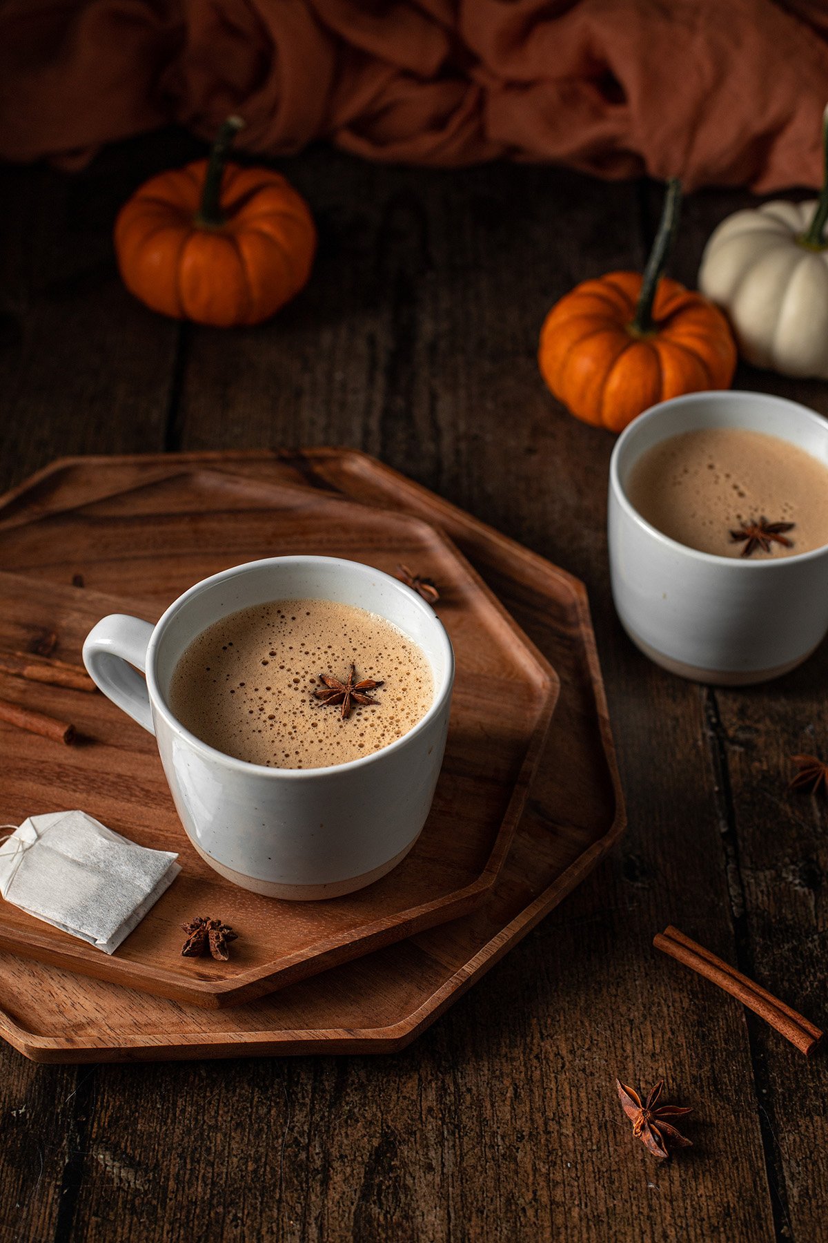 Two cups of pumpkin spice latte on a wooden table.