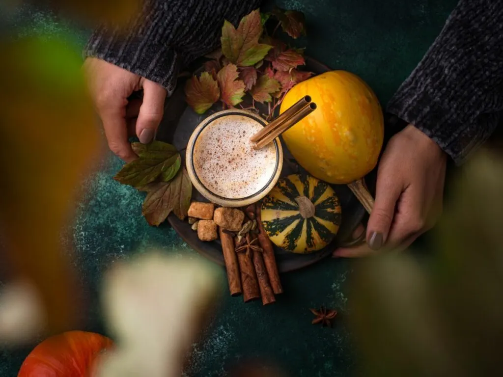 A woman's hands holding a cup of pumpkin spice latte.