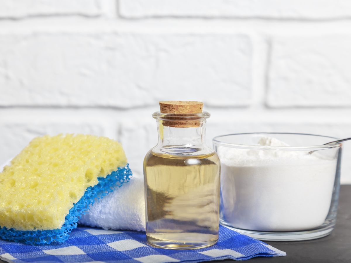 Cleaning liquid, baking soda, and sponge on a table for removing stains from carpet.