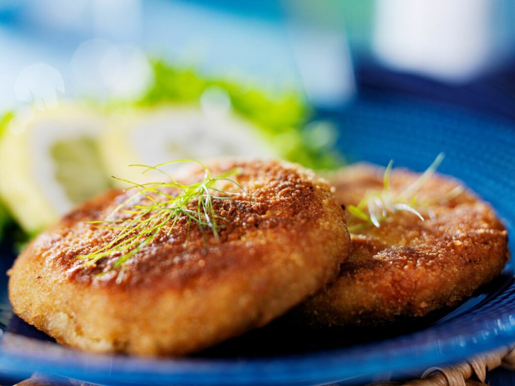 Two fried crab cakes on a blue plate.