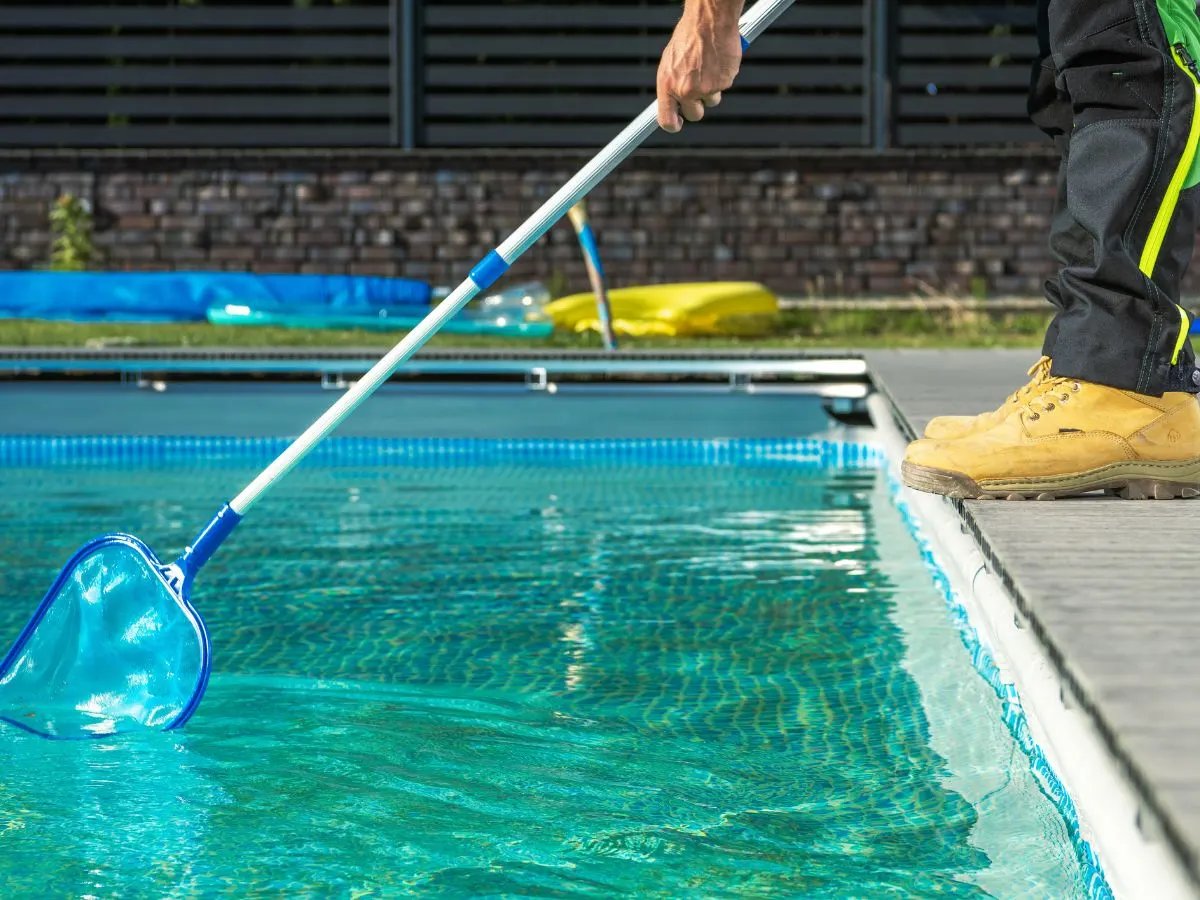 A man cleaning a pool with a net.