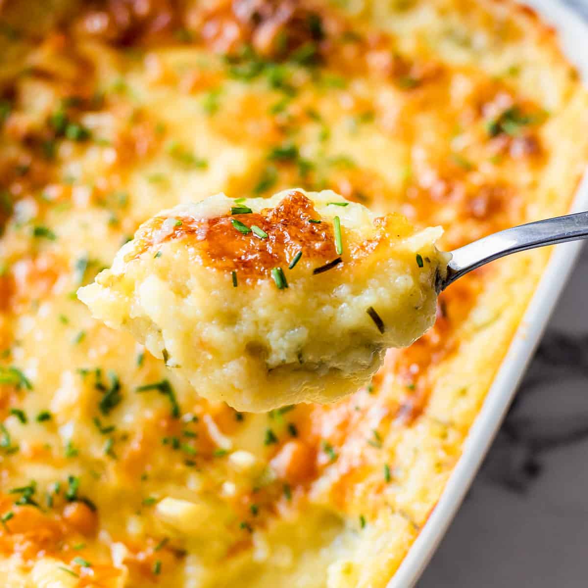 A spoonful of mashed potatoes in a casserole dish.