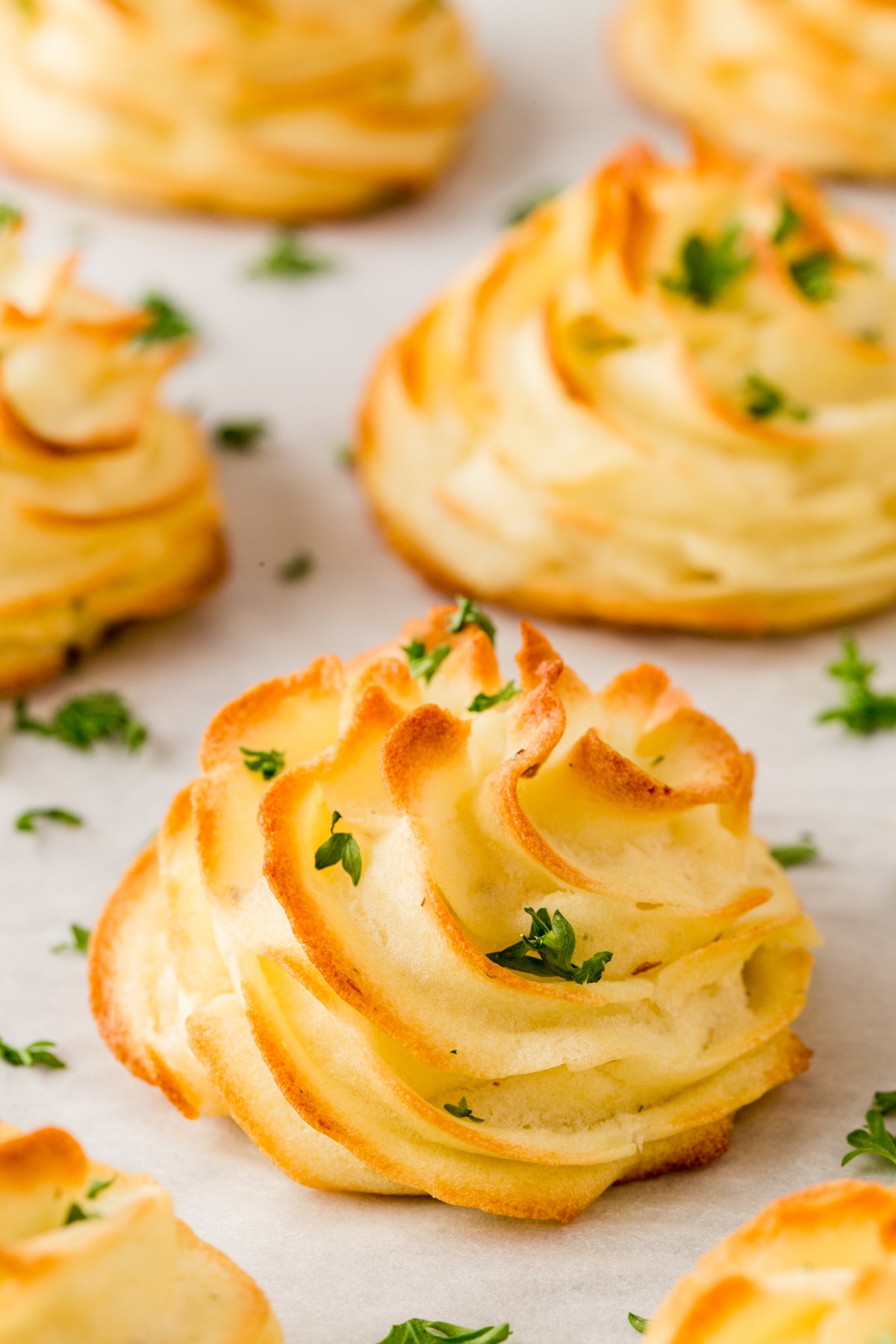 Golden brown duchess potatoes with parsley on a baking sheet.