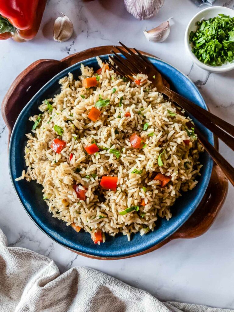 A serving plate of rice with red bell peppers and two forks.